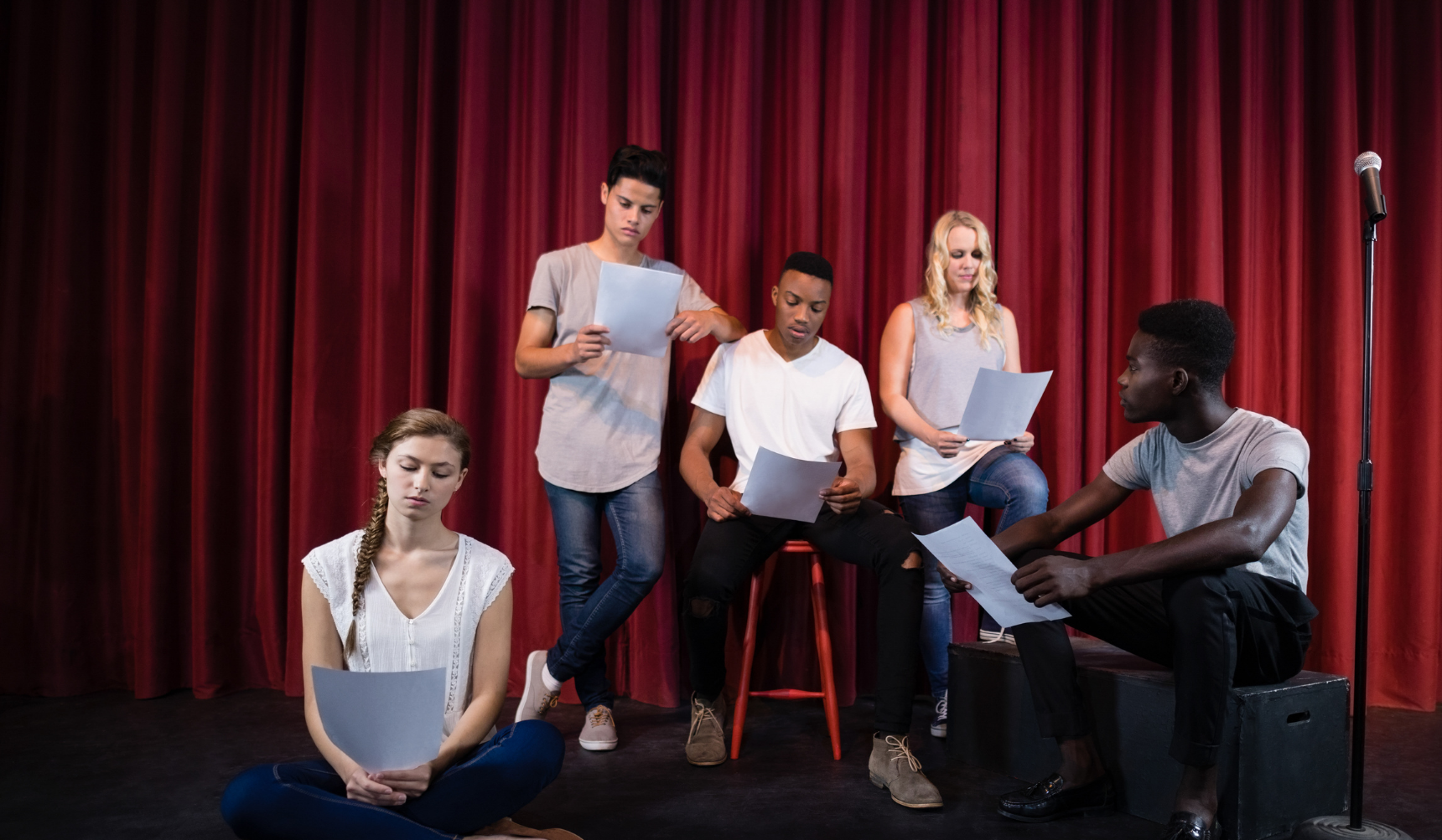 Drama pupils on stage reading scripts