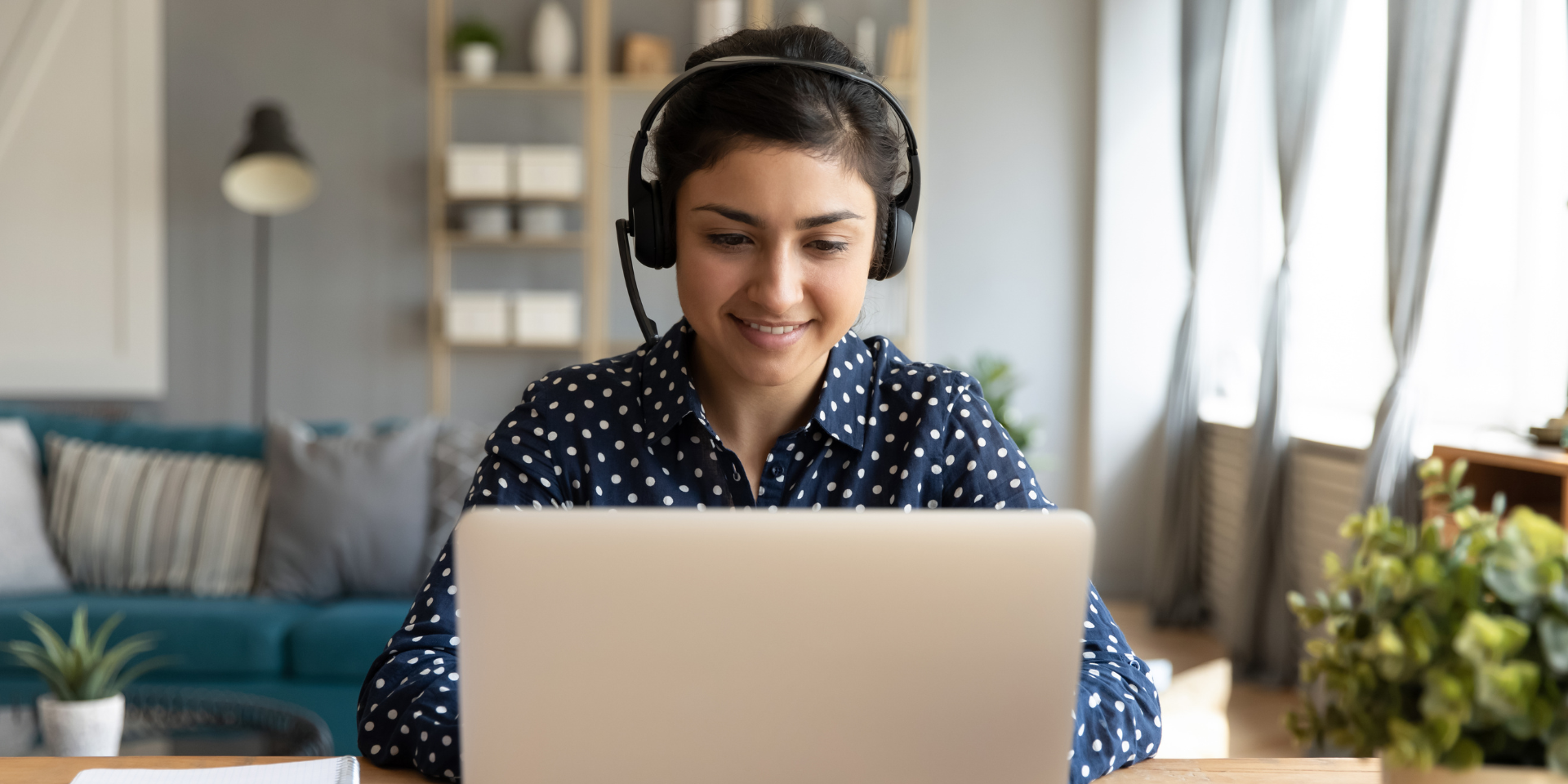 White woman in headset facing laptop smiling