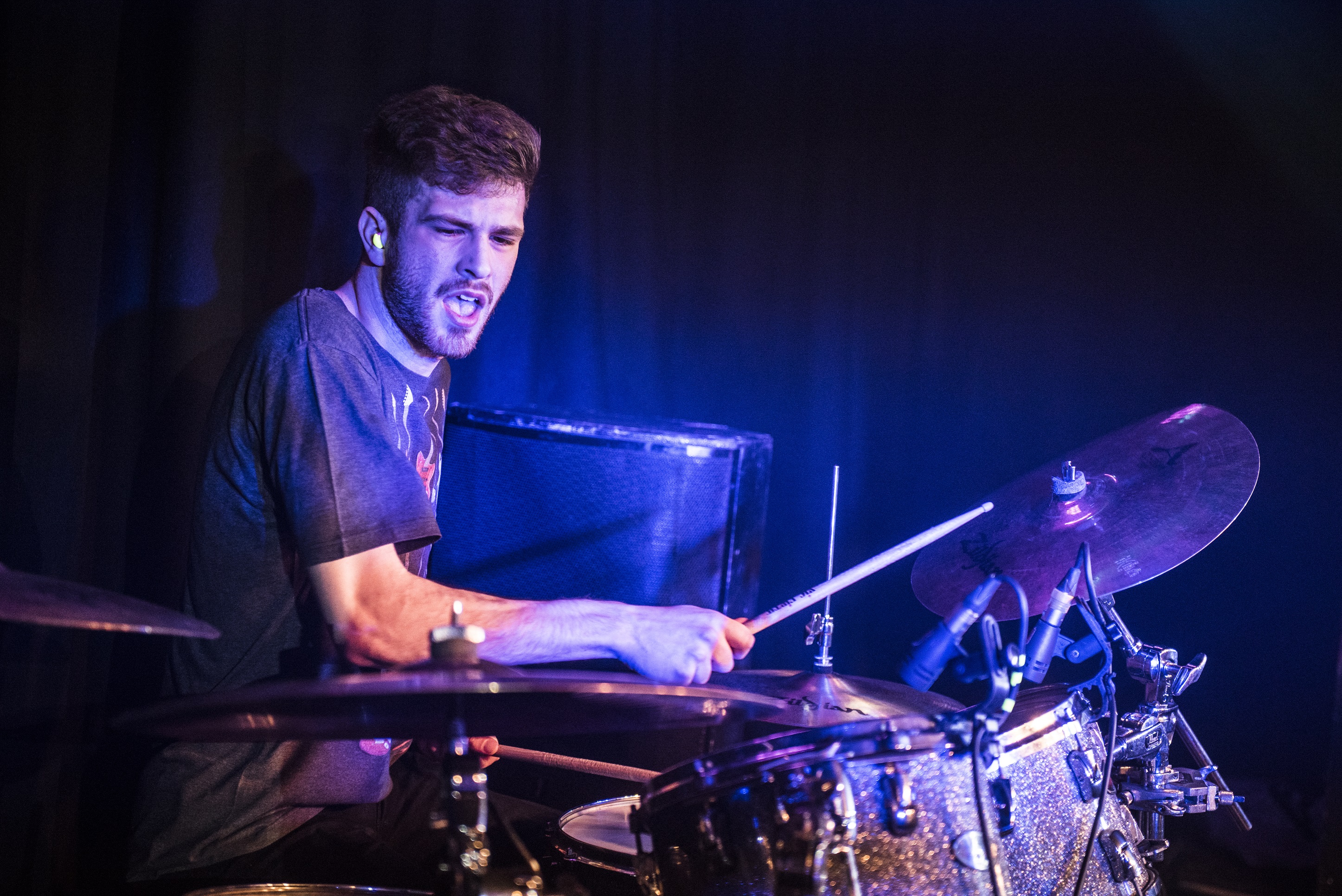 Man playing the drums under a blue light